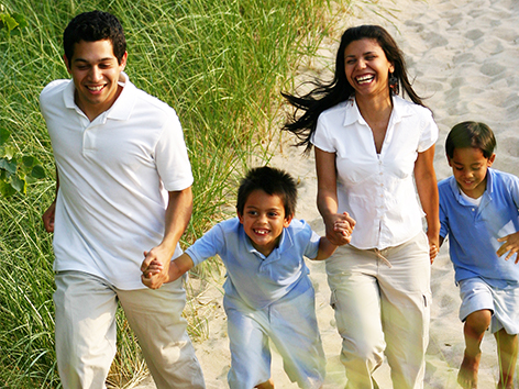 Latino family smiling and walking on the beach 