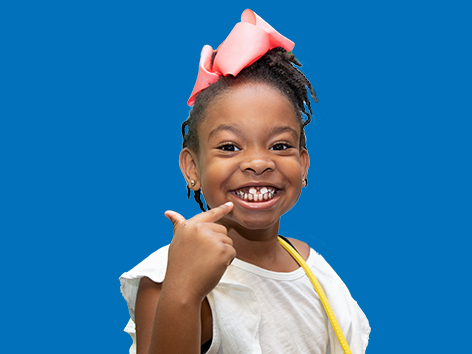 African American girl smiles and points to her teeth