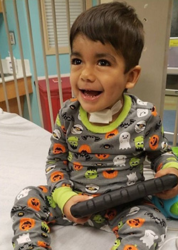 Toddler smiling and holding an electronic game device.